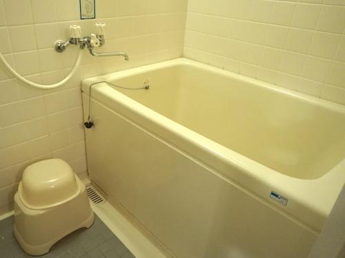a white bath tub in a bathroom with a toilet at Arima Onsen Takayamaso Hanano in Kobe