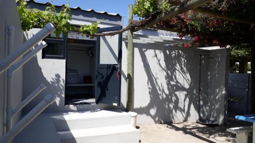 ein Eingang zu einem blauen Schuppen mit einer Tür und Treppe in der Unterkunft Shell Cottage a stone's throw from the beach in Langebaan