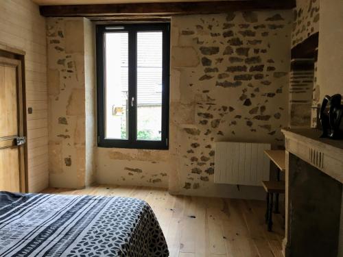 a bedroom with a bed and a window at La Rénovée d’Antan in Avallon