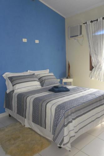 a bedroom with a bed with a blue wall at Pousada da Rose Paraty in Paraty