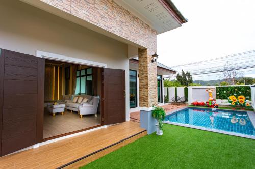 a backyard with a swimming pool and a house at Uzeason Poolvilla Sattahip in Sattahip