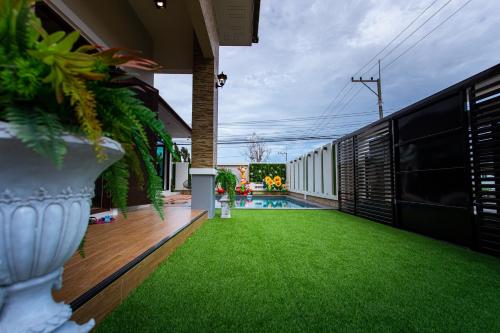 a backyard with a green lawn and a pool at Uzeason Poolvilla Sattahip in Sattahip