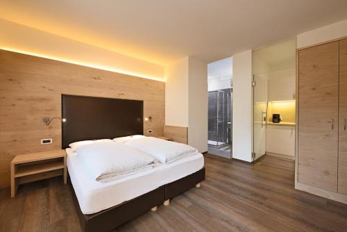 a large bedroom with a large white bed and wooden floors at Garni Kostner in Ortisei