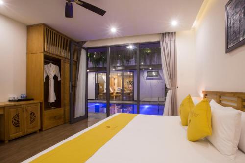 a bedroom with a large white bed and a window at MaiChi Villa Hoi An in Hoi An