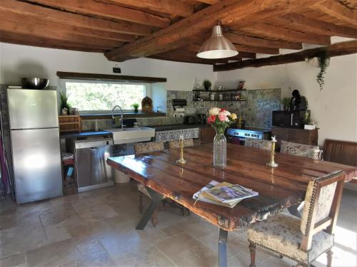 une cuisine avec une table en bois et un réfrigérateur dans l'établissement Domaine LVD avec SPA, bois et rivière privée, à La Bloutière