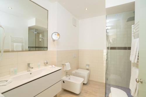 a bathroom with a sink and a toilet and a mirror at Hotel Schweizerhof Pontresina in Pontresina