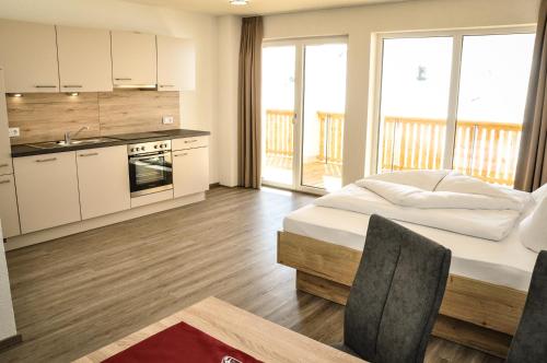 a bedroom with a bed and a kitchen with a balcony at apart-wolf-arlberg in Warth am Arlberg