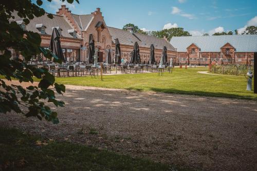 a building with a yard with tables and umbrellas at Colonie 7 - Gastenkamers in Merksplas