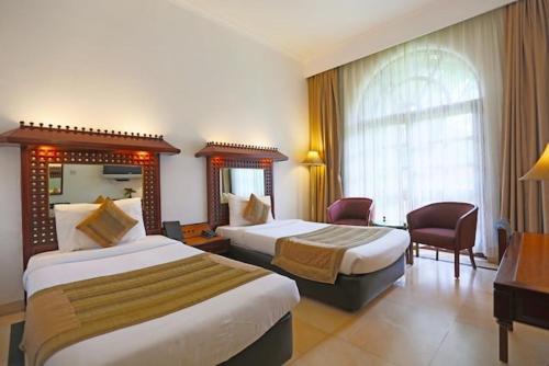 una camera d'albergo con due letti e una finestra di Ashok Country Resort a Nuova Delhi
