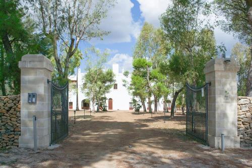 a gate in front of a white building with trees at Tenuta Afra in Squinzano