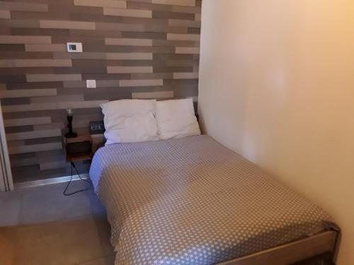 ein kleines Bett mit zwei Kissen in einem Zimmer in der Unterkunft Joli 2 pièces esprit loft moderne in Pau