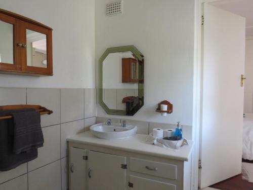 a bathroom with a sink and a mirror at Wiltshire Cottage in Port Alfred