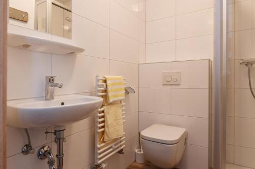 a white bathroom with a sink and a toilet at Pension Grenzenlos in Selfkant