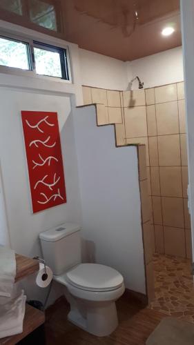a bathroom with a toilet and a red painting on the wall at Tropical Paradise Bungalows in Pital