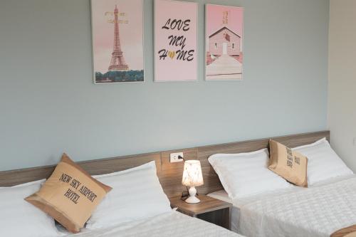 two beds in a room with posters on the wall at New Sky Airport Hotel in Noi Bai