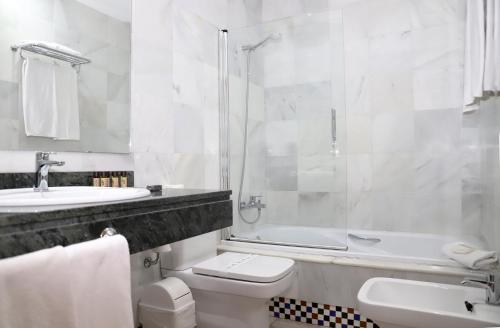 a white bathroom with a toilet and a sink at Hostal Doña Lola Marina in Zahara de los Atunes