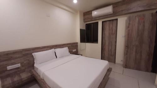 a bedroom with a white bed and a wooden wall at Hotel Dwarawati in Dwarka