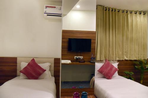 a hotel room with two beds and a television at HOTEL RAJPATH INN in Mehsāna