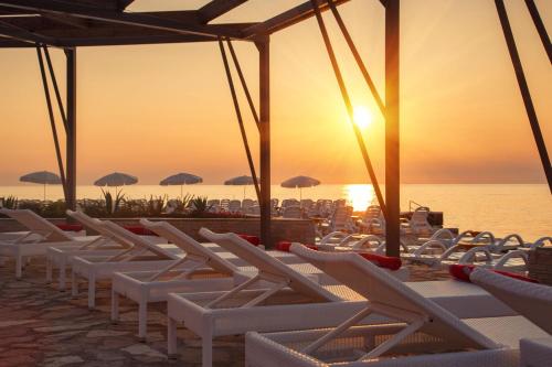 a row of white chairs on the beach at sunset at Residence Umag Plava Laguna in Umag