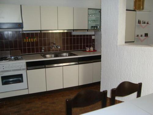 a kitchen with white cabinets and a sink and a stove at Apartments Kristina in Klenovica