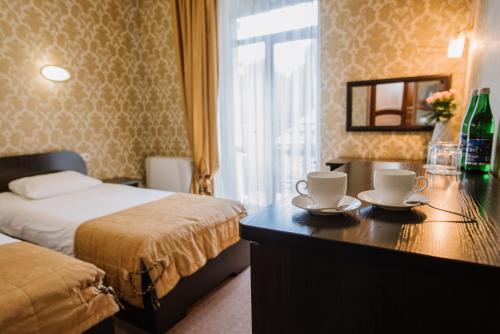 a hotel room with a bed and a desk with two cups at Курортний Готель Золота Корона in Truskavets