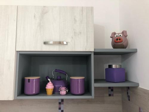 a kitchen cabinet with purple pots and pans at Casa Violet per Civita in Bagnoregio