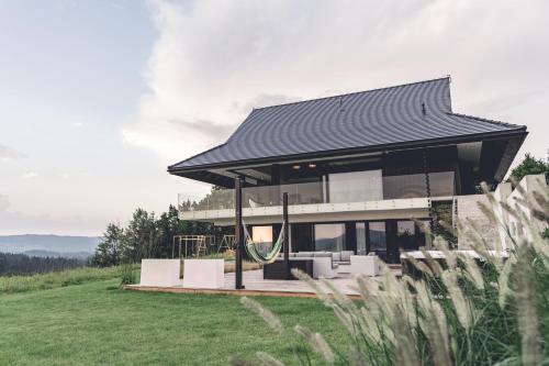 a house with a black roof on top of a field at Villa Panorama - Szklany Dom in Jaworzynka