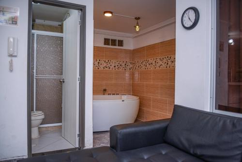 baño con bañera, aseo y reloj en Apartment Carrera 301, en Medellín