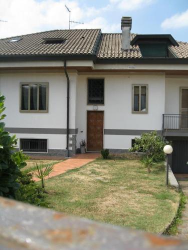 a white house with a brown door and a yard at La casa dei pini in Malnate