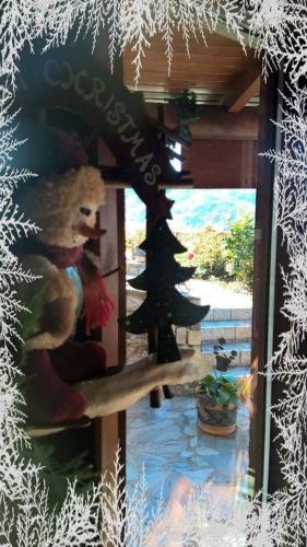 a teddy bear sitting in a window with a christmas tree at Alagonia Country Homes in Alagonía