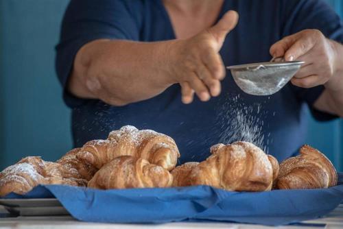 a person is sprinkling powdered sugar on a plate of pastries at Casa del Sole in Nicotera Marina