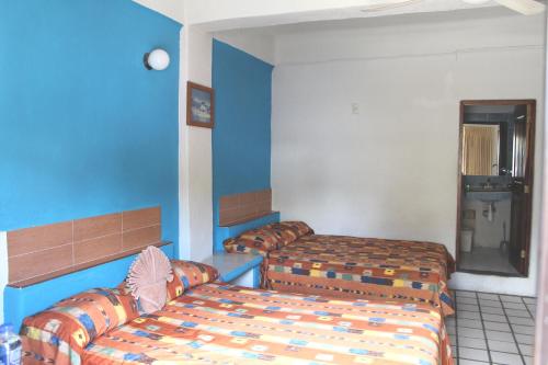 a hotel room with two beds and blue walls at Hotel Arrecife Huatulco Plus in Santa Cruz Huatulco
