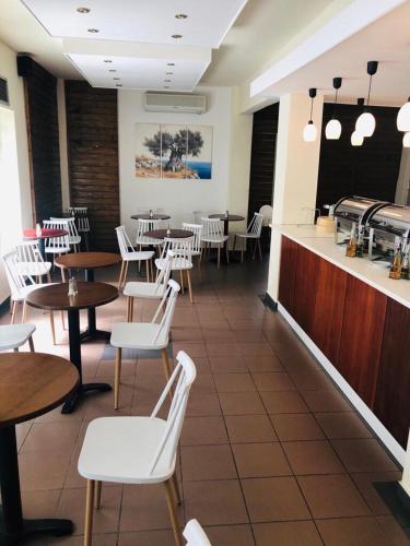 a restaurant with tables and white chairs and a counter at SimOtel Ermis in Hanioti