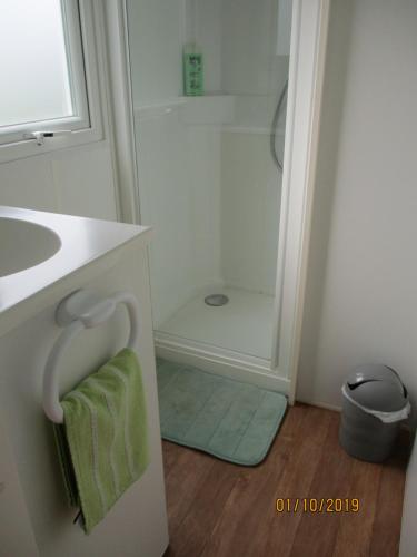 La salle de bains est pourvue d'un lavabo, d'une douche et d'une serviette verte. dans l'établissement Les Mobile home de KERROYAL, à Garlan