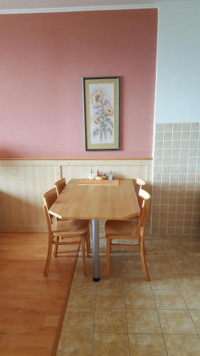 a table and chairs in a room with a pink wall at AD Šafrán č. 25 in Donovaly