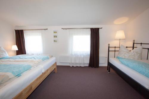 a bedroom with two beds and two windows at Haus Dreischläfer deluxe in Dreschvitz