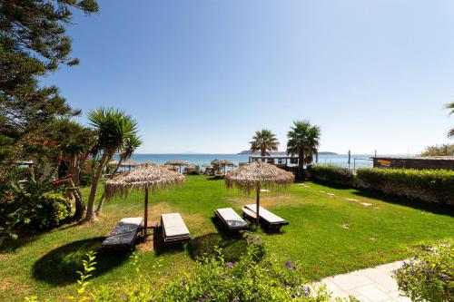 a group of benches with umbrellas and the ocean at Golden Beach Hotel in Chrissi Akti