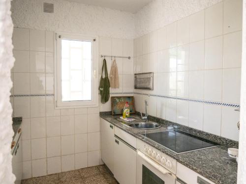 cocina de azulejos blancos con fregadero y ventana en Monte Rojo en Corralejo