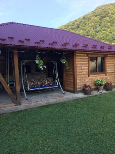 a log cabin with a purple roof and a yard at Котедж Relax Yaremche in Yaremche