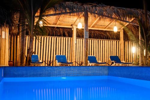 a swimming pool with blue chairs in a building at Maria Jose Bungalows in Zorritos