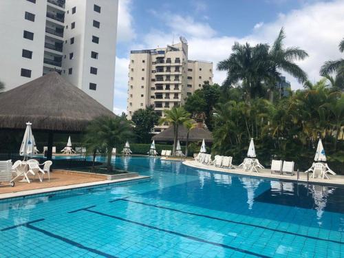 a large swimming pool with white chairs and buildings at Apartamento lazer na rua da praia in Riviera de São Lourenço