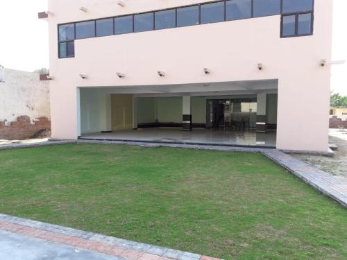 a white building with a green lawn in front of it at Yog Bhawan in Greater Noida