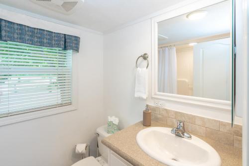 a bathroom with a sink and a toilet and a window at Sun Outdoors Petoskey Bay Harbor in Petoskey