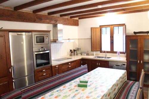 a kitchen with a table and a stainless steel refrigerator at Casa Rural Reserva Saja-Besaya in Villayuso de Cieza