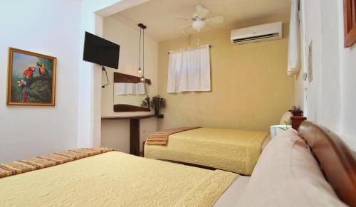 a hotel room with two beds and a tv at Rainforest Haven Inn in San Ignacio