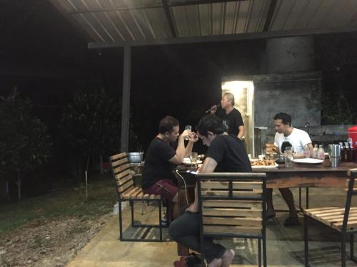 a group of people sitting at a table at night at ชลลดา ริเวอร์ โฮมสเตย์ แก่งกระจาน in Ban Wang Malako