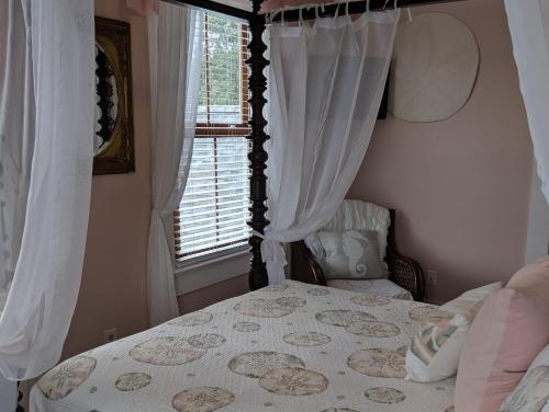 a bedroom with a bed with a canopy and a window at Surf Song Bed & Breakfast in Tybee Island