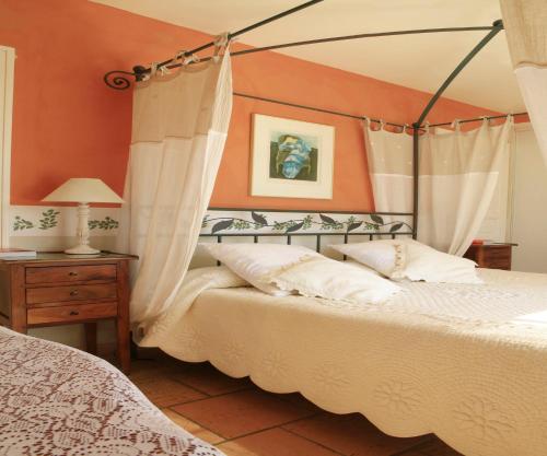 two beds in a bedroom with orange walls at Mas des Figues #PhilippeArtist #bio-organiccertified #potagerbio #huiledolivebio #mediterraneandietbrunch #farmtofork #homemadecooking #biodiversity #roseraie #ecologicalgarden #agritourism #ecotourism #farmstay #guesthouse #saintremydeprovence #Alpilles in Saint-Rémy-de-Provence