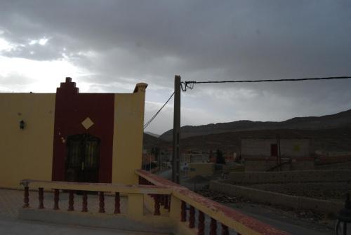 a building with a fence and mountains in the background at Auberge Tafilalt Bouzmou Bouzmou in Imilchil