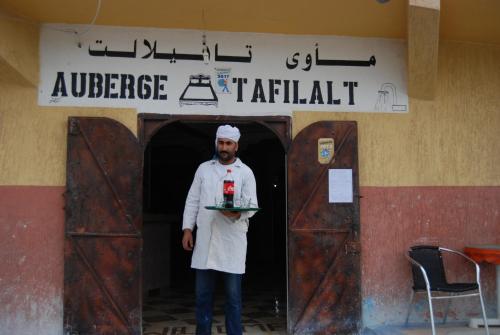a man standing in a doorway with a tray of food at Auberge Tafilalt Bouzmou Bouzmou in Imilchil